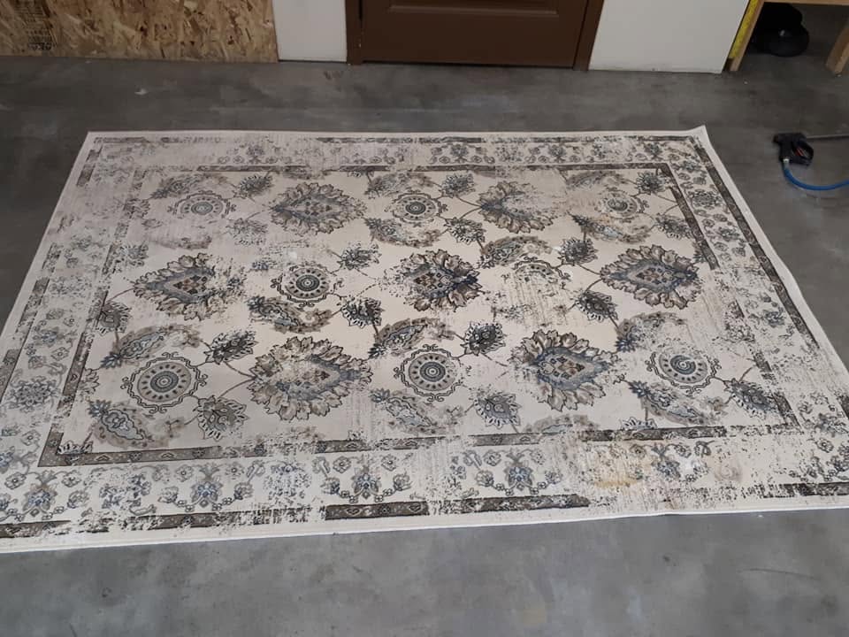 Large patterned area rug laid flat for dry soil removal before cleaning